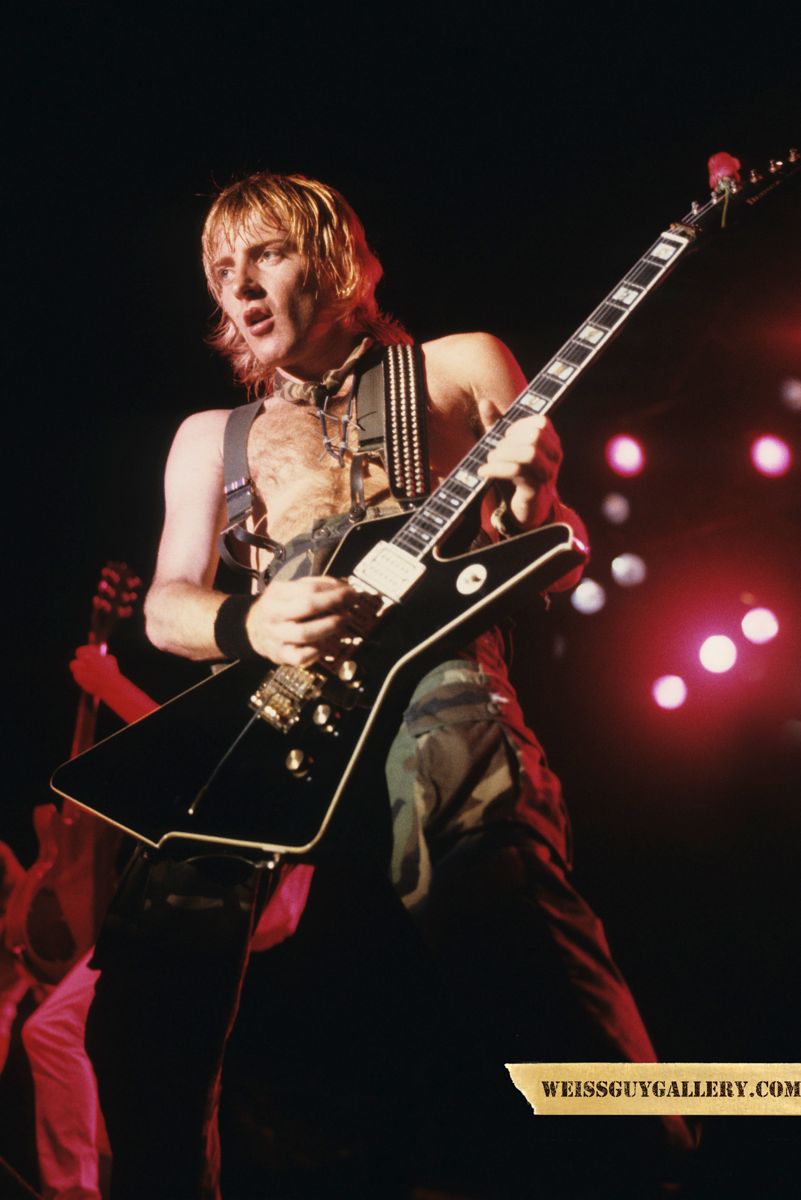 Me (Phil Collen) guitarist of Def Leppard Pyromania Tour 83: Here I am onstage with my Ibanez Destroyer which you can hear among other things on the solos of Photograph, Rock of Ages, and Foolin. An interesting thing about what Im wearing-my suitcase with all of my clothes was stolen from a Florida hotel and I only had shorts on when I made the discovery. Some fans took me to an army surplus store hence the camo fatigues which became my staple for the rest of the Pyromania tour.